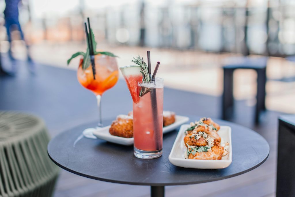 Colorful cocktails and delicious appetizers on a stylish outdoor table, perfect for a summer gathering.